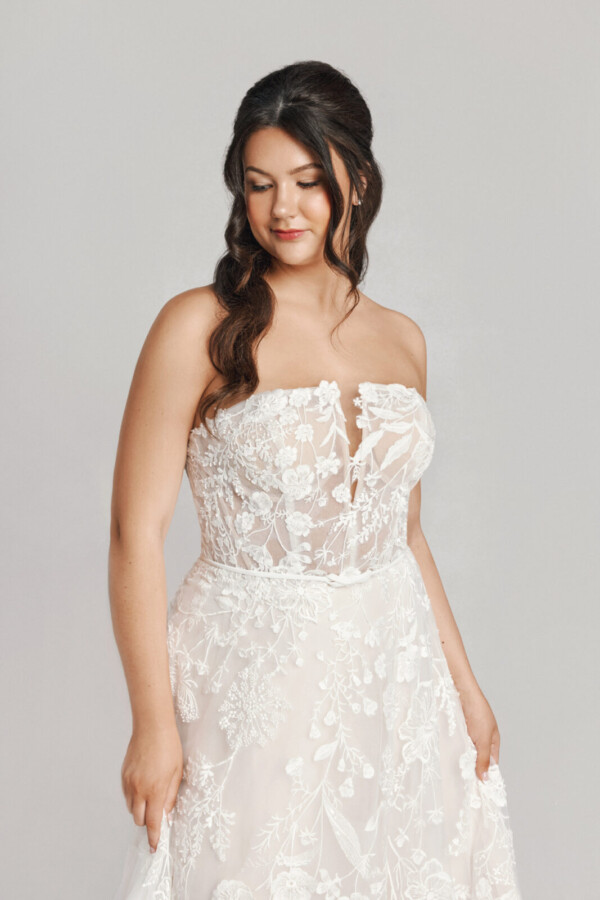 A bride in a white fitted floral strapless dress.
