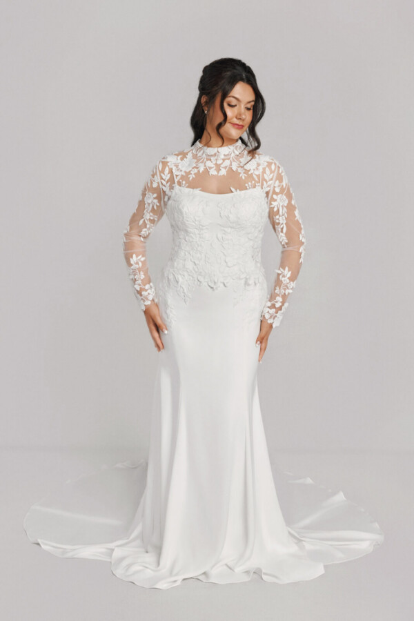 A bride in a white fitted slim strap floral lace dress with sheer floral sleeves.