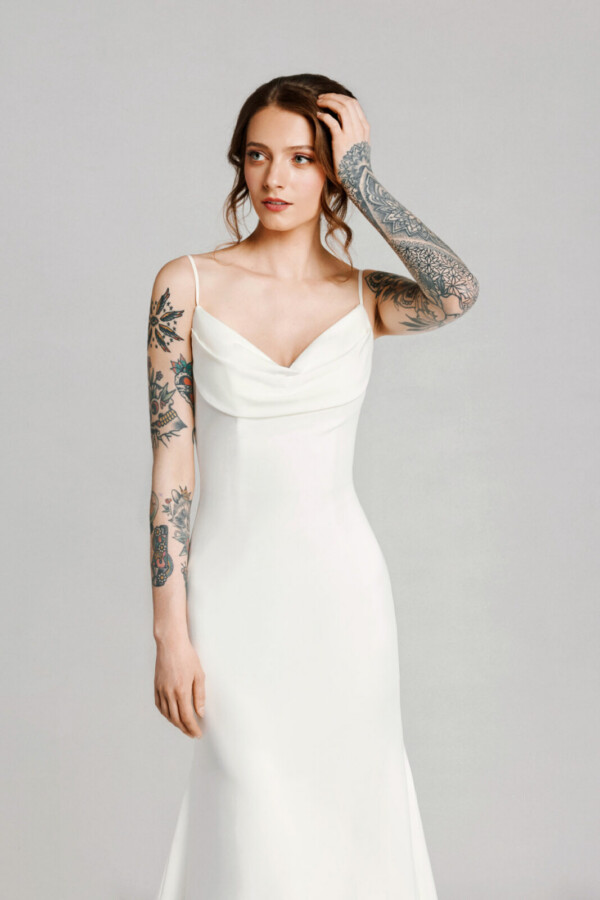 A bride in a white flowy lace floral deep v cut dress with tattoos.