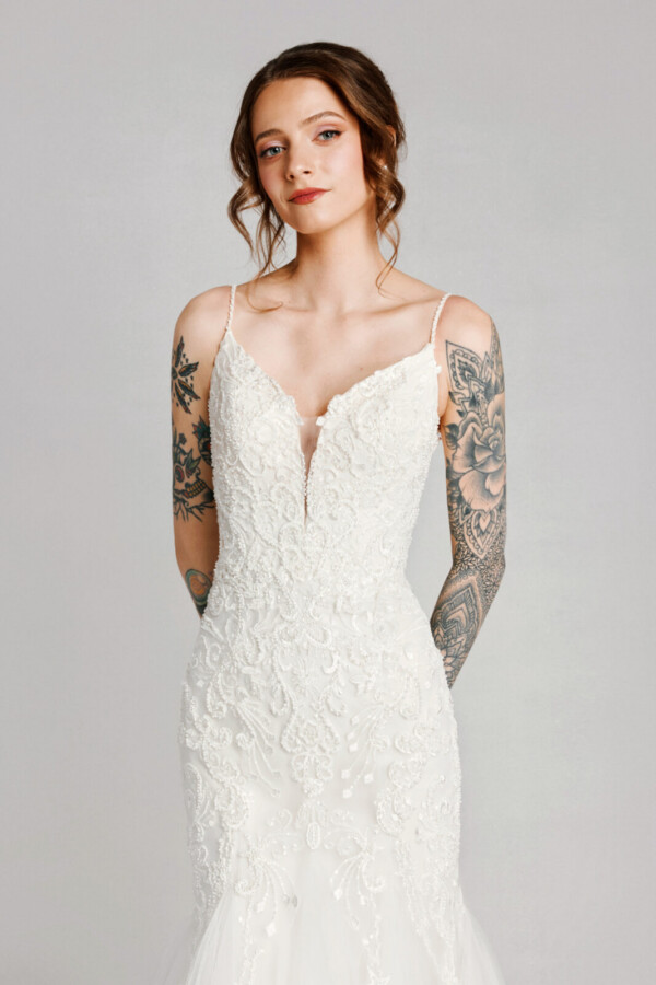 A bride in a white flowy lace floral deep v cut dress with tattoos.