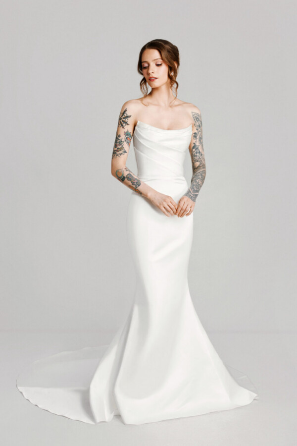 A bride with tattoos in a white fitted slim strapless dress.