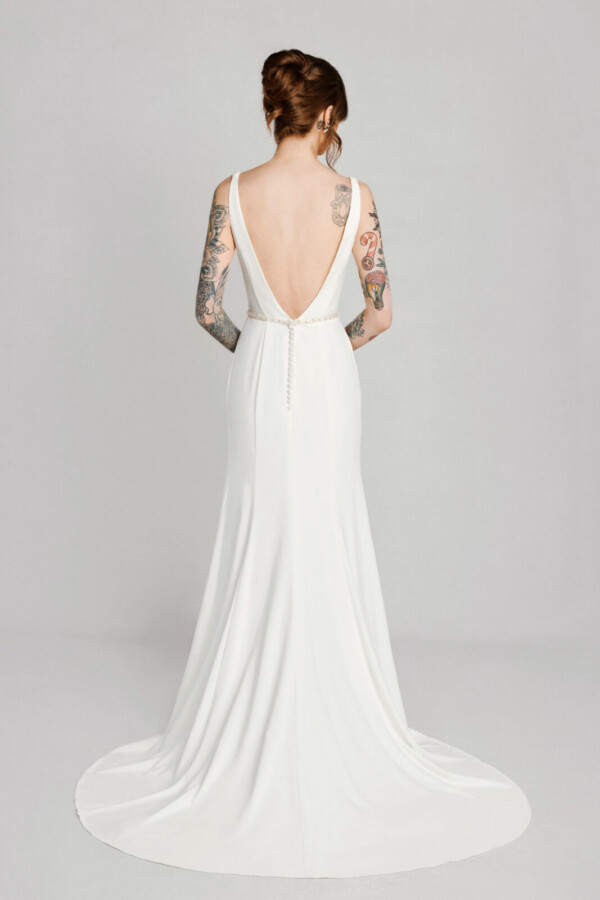 A bride with tattoos in a white fitted slim backless dress.