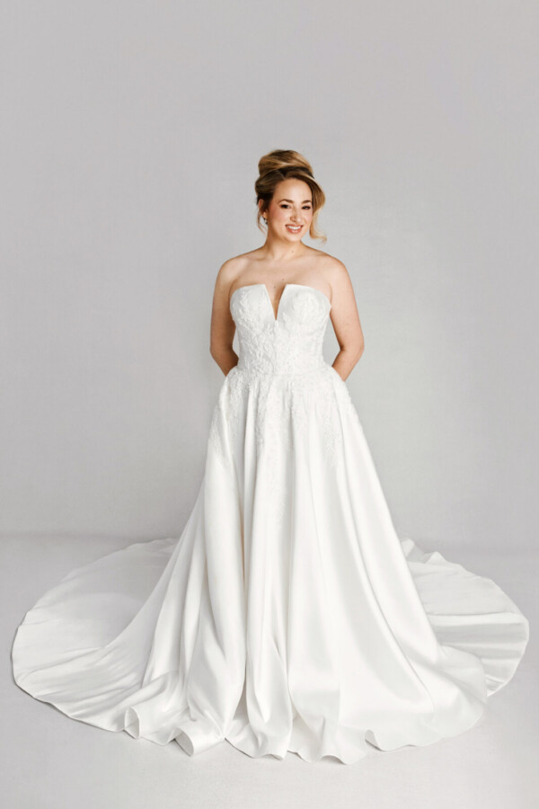 A bride in a white fitted deep v cut strapless floral lace dress.