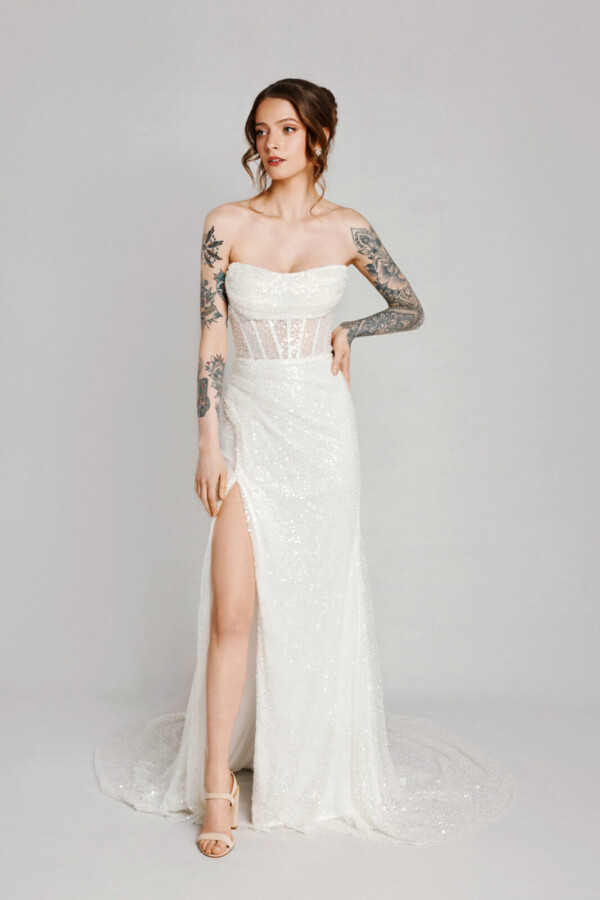 A bride with tattoos in a white fitted lace floral dress with leg slit.