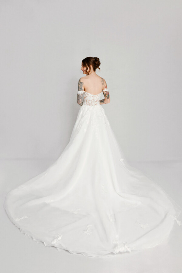 A bride with tattoos in a white fitted off the shoulder dress.