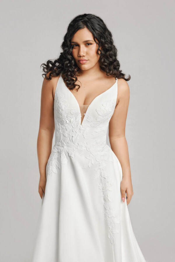 A bride in a white flowy lace floral deep v cut dress.