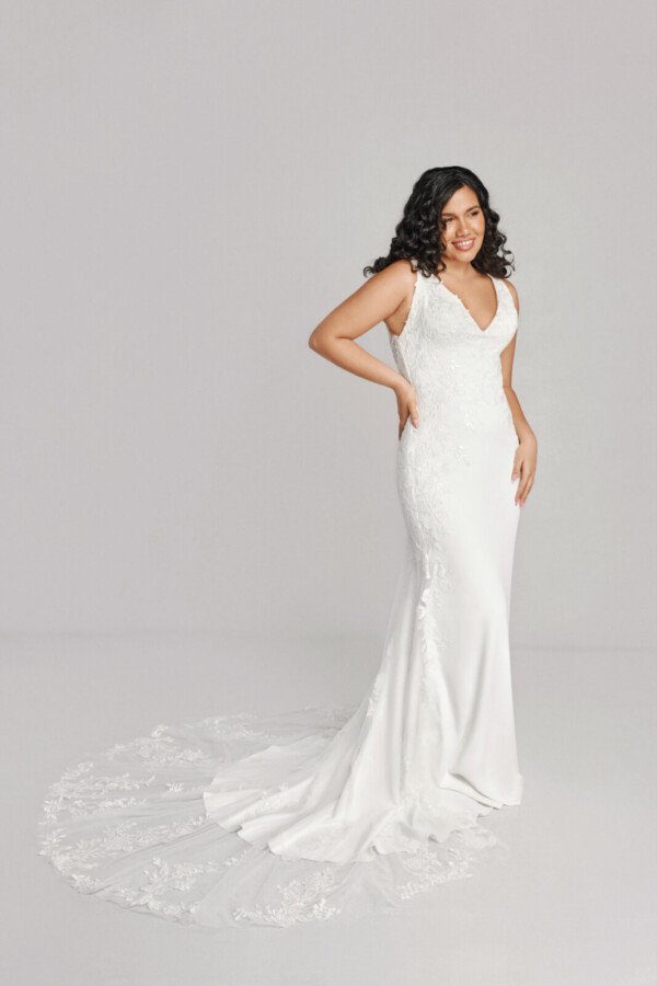 A bride in a white fitted lace floral deep v cut dress.