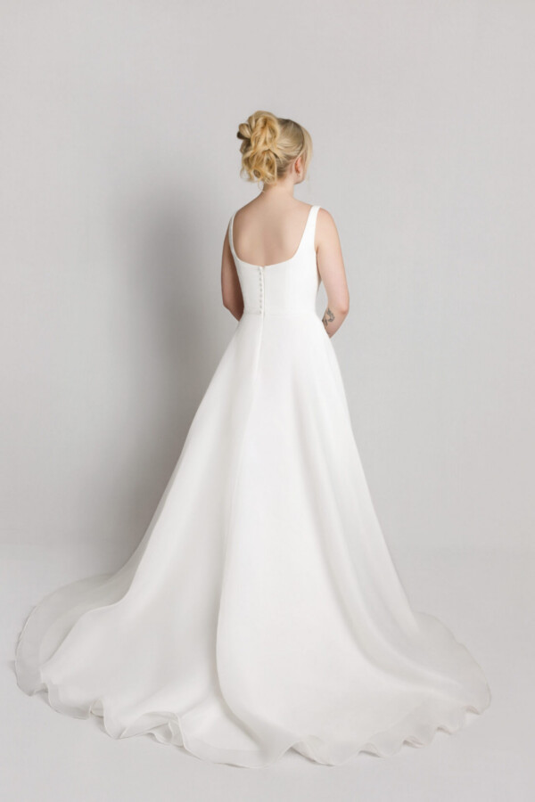 Back view of a bride in a soft tulle wedding gown with thin straps and a flowing train.