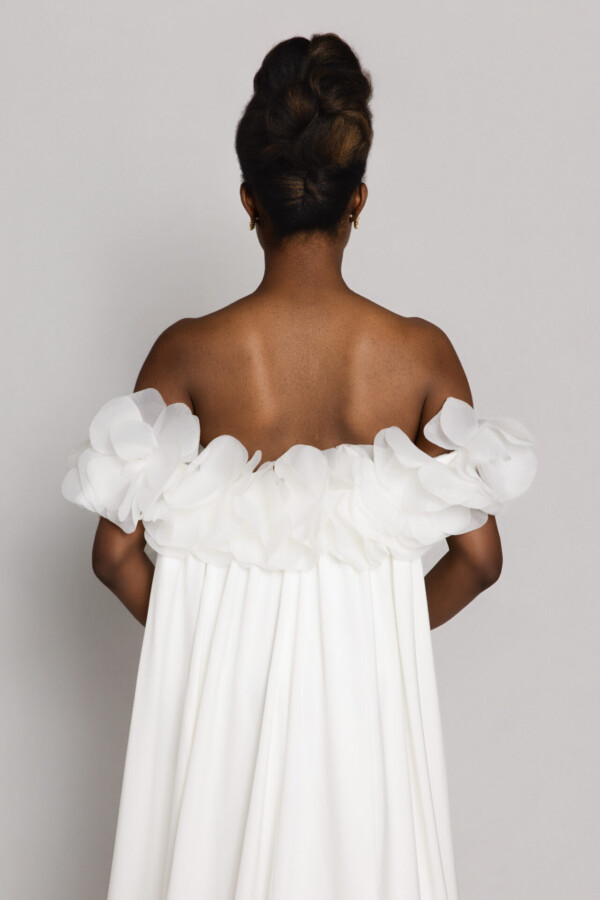 Back view of a bride wearing an off-the-shoulder wedding dress with ruffled sleeves and an updo hairstyle.