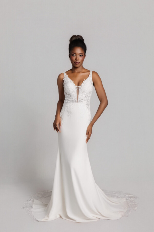 Bride wearing a sleeveless white wedding gown with a deep V-neckline and fitted silhouette, standing against a neutral background.
