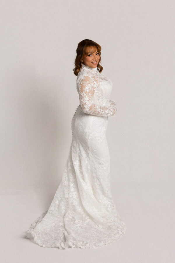 Side view of a bride wearing a long-sleeve lace wedding gown with a fitted silhouette and lace train.